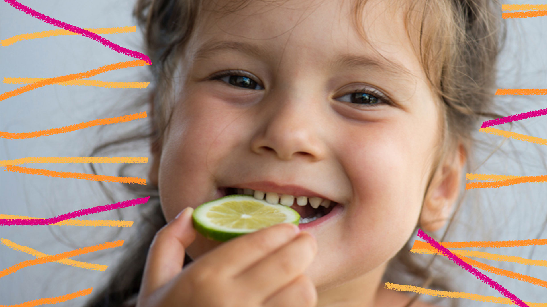 Alimentos para imunidade: foto de criança de cabelos loiros, que sorri ao experimentar um pedaço de limão.