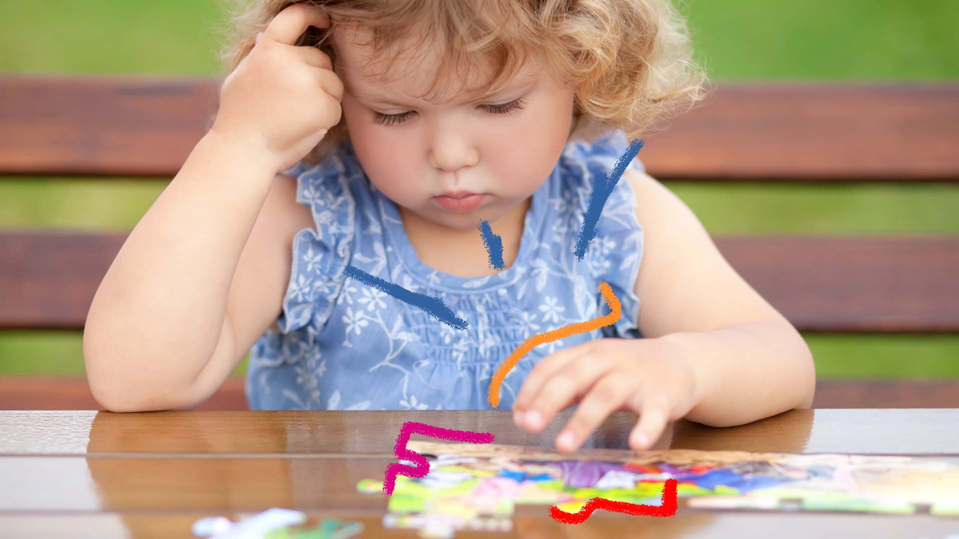 Filhos no trabalho: foto de uma criança que olha para um jogo em cima de uma mesa e coloca uma das mãos na cabeça.