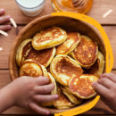 Mãos de criança comendo panquecas feitas em casa em uma tigela cheia