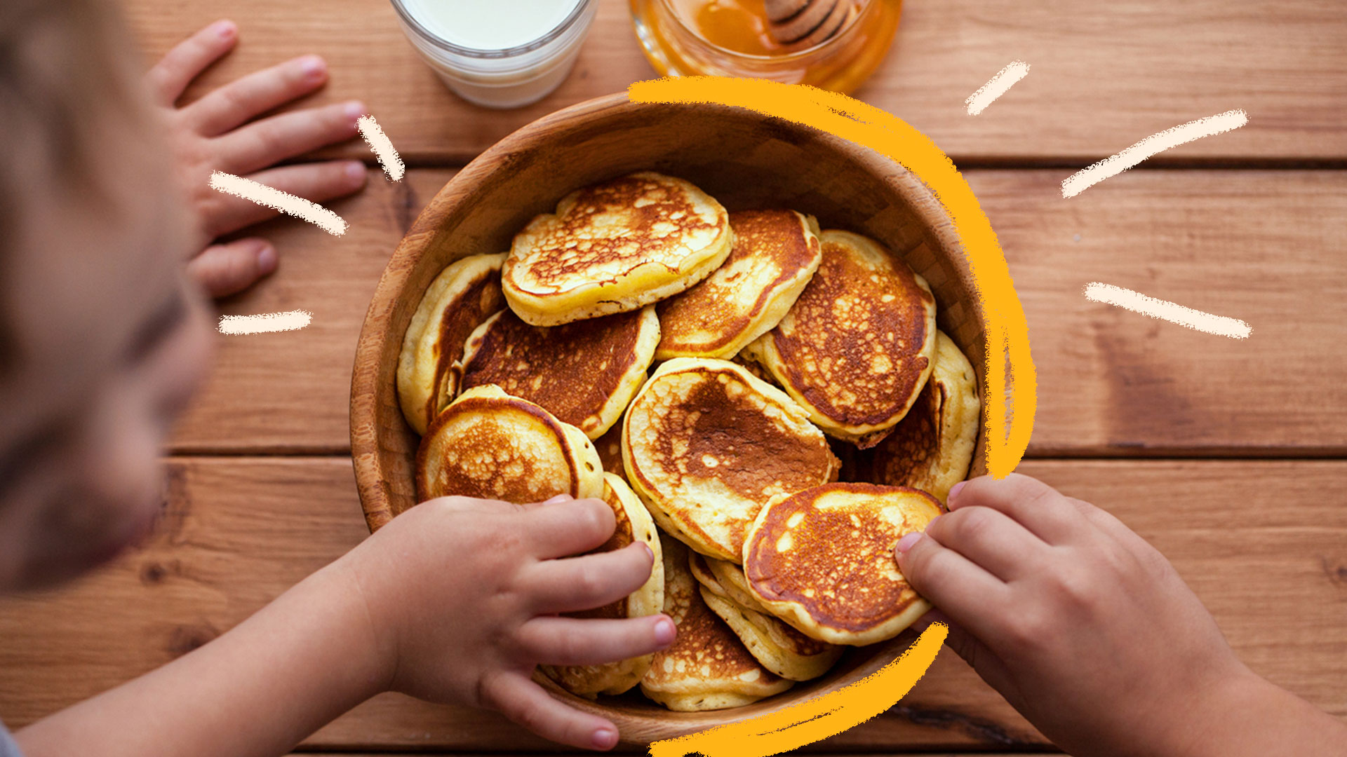 Mãos de criança comendo panquecas feitas em casa em uma tigela cheia