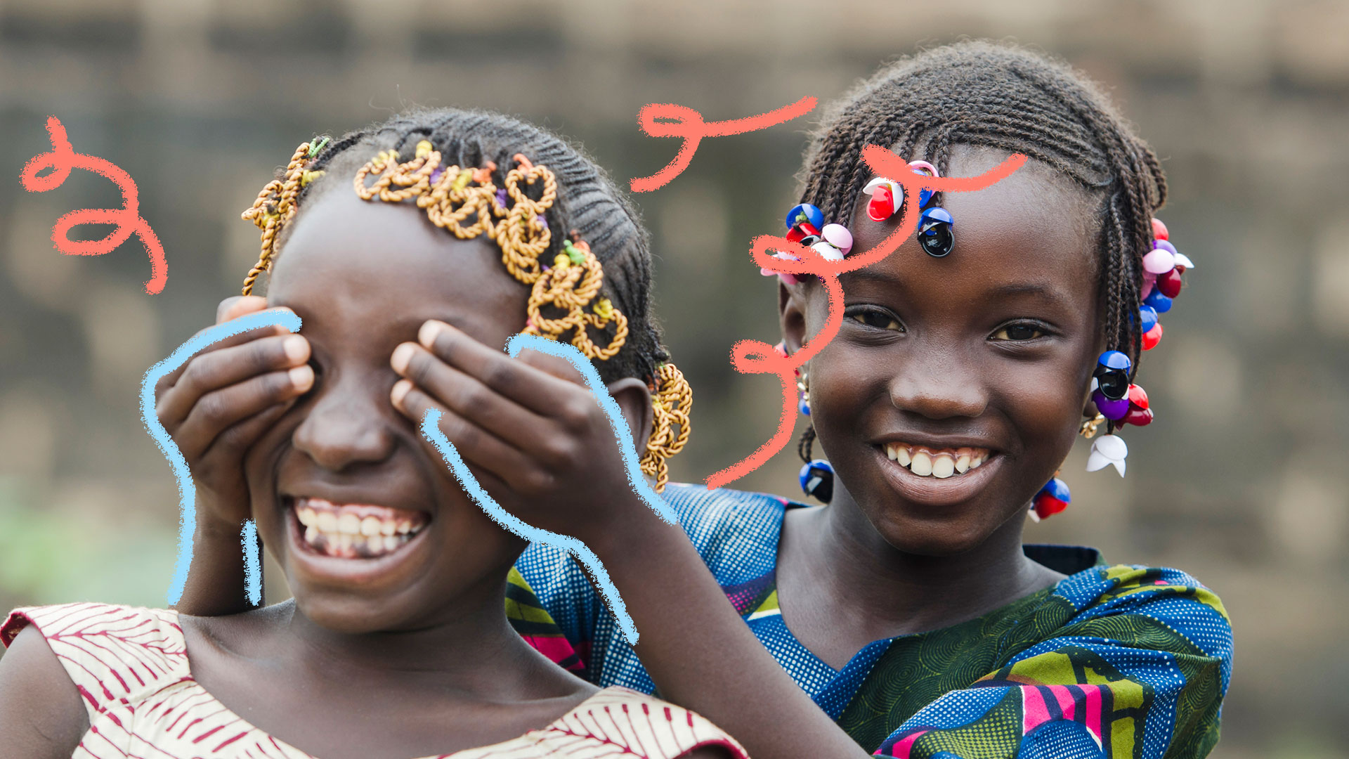Brincadeiras africanas: foto de duas meninas negras, que brincam de tapar os olhos uma da outra. Elas estão sorrindo e se divertindo.