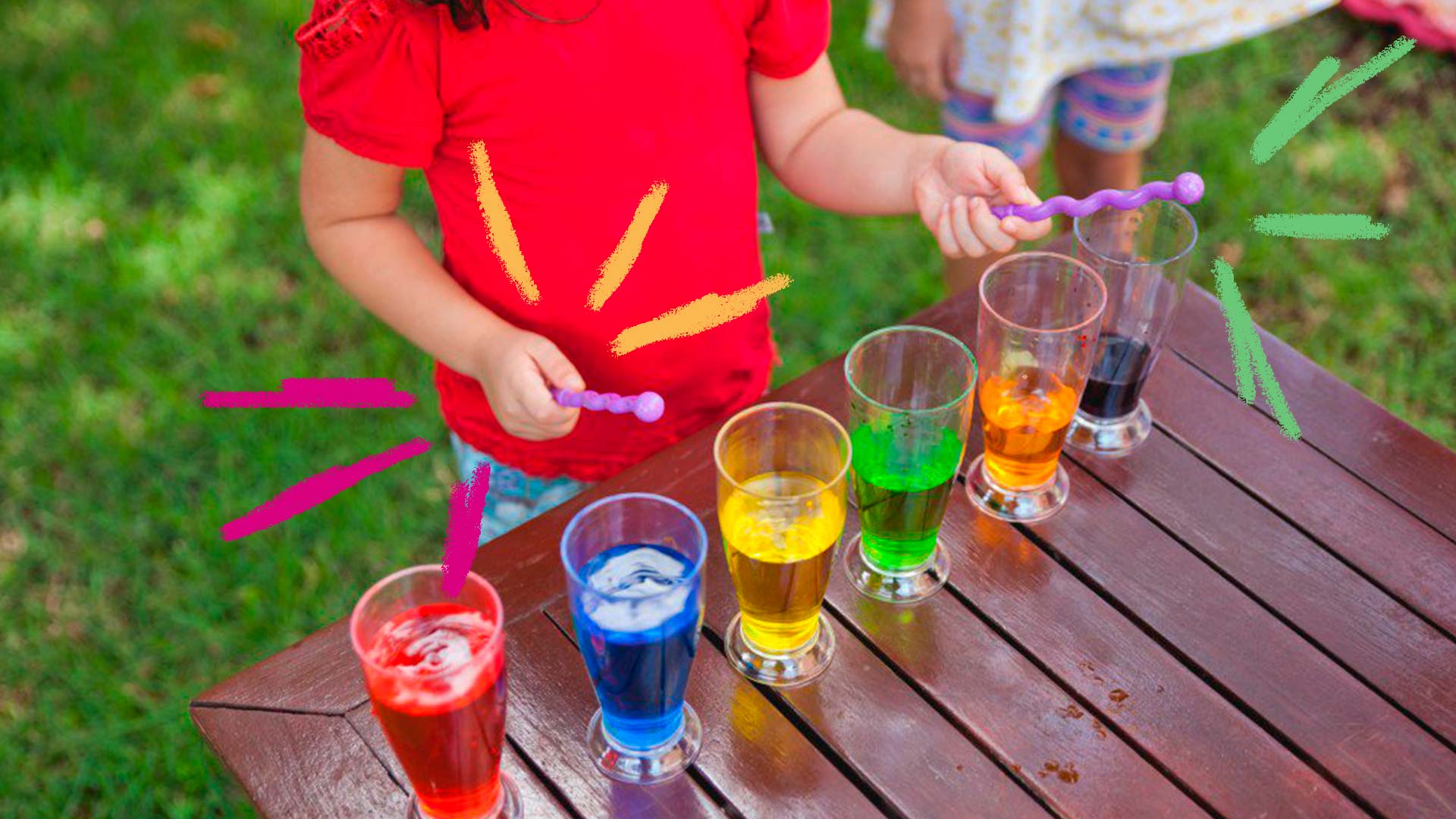 criança tocando xilofone feito de copos de água com diferentes líquidos coloridos.