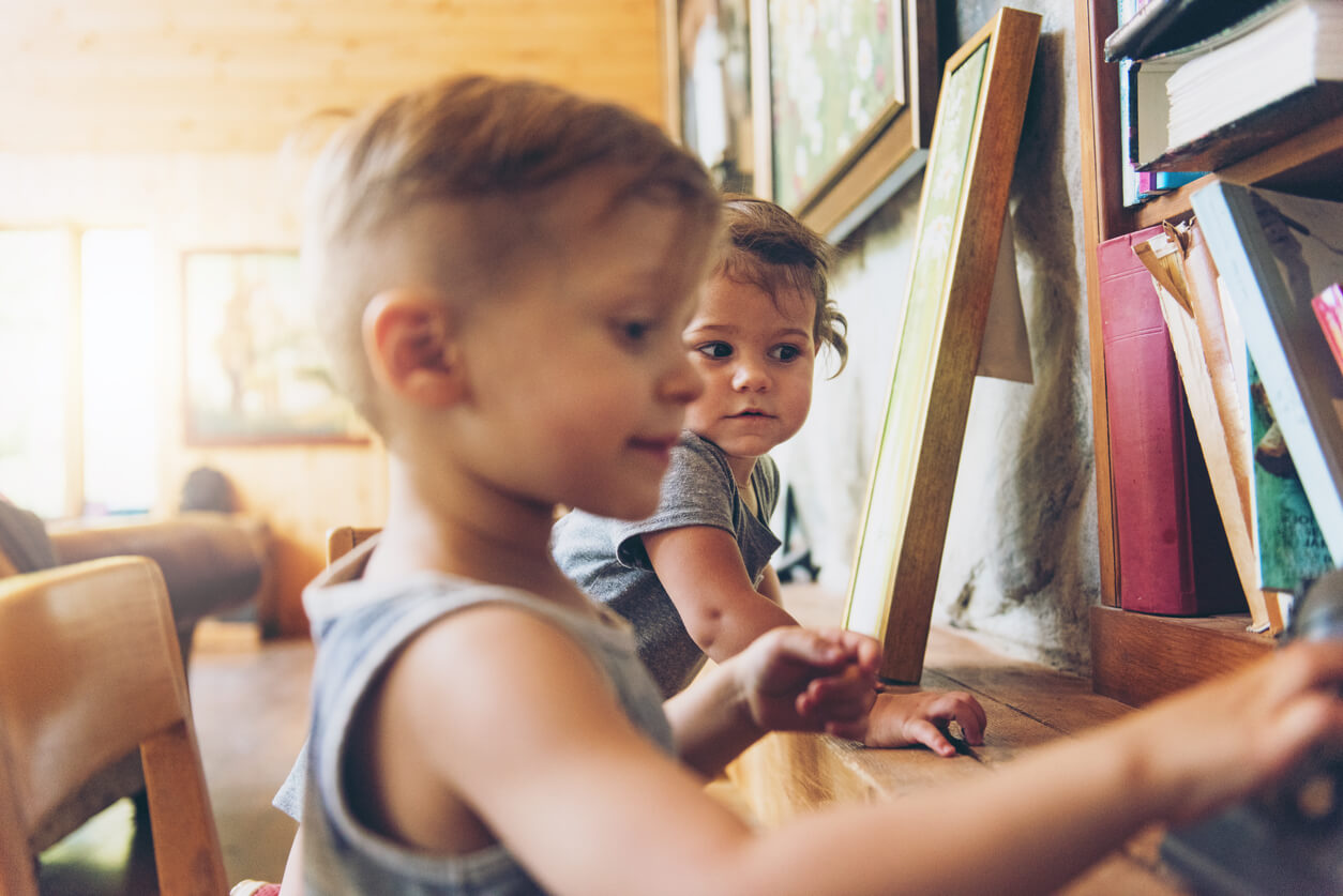 Duas crianças brincam em frente ao um cavalete de pintura