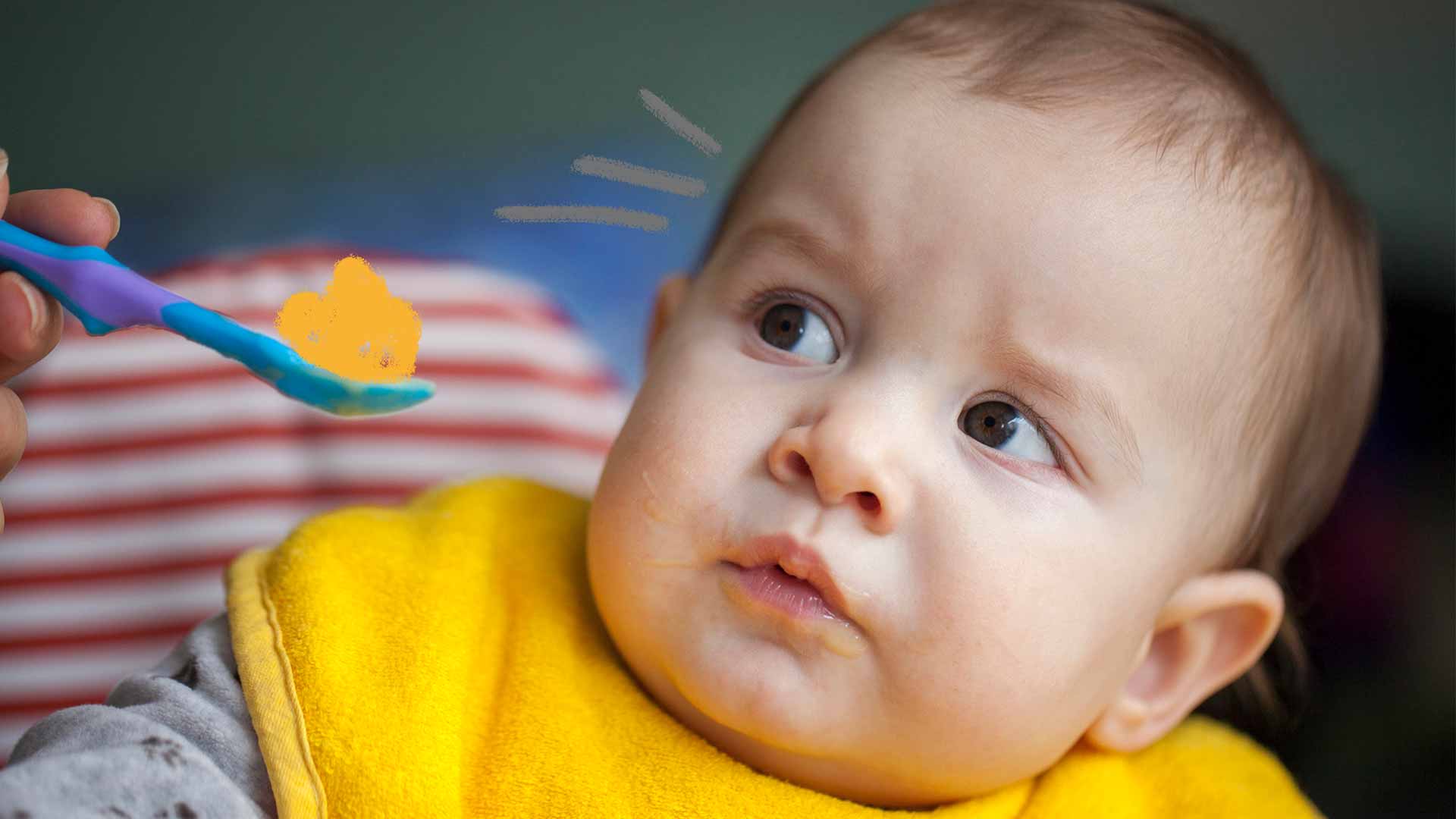 Um bebê olha desconfiado para uma colher de comida que está sendo oferecida.