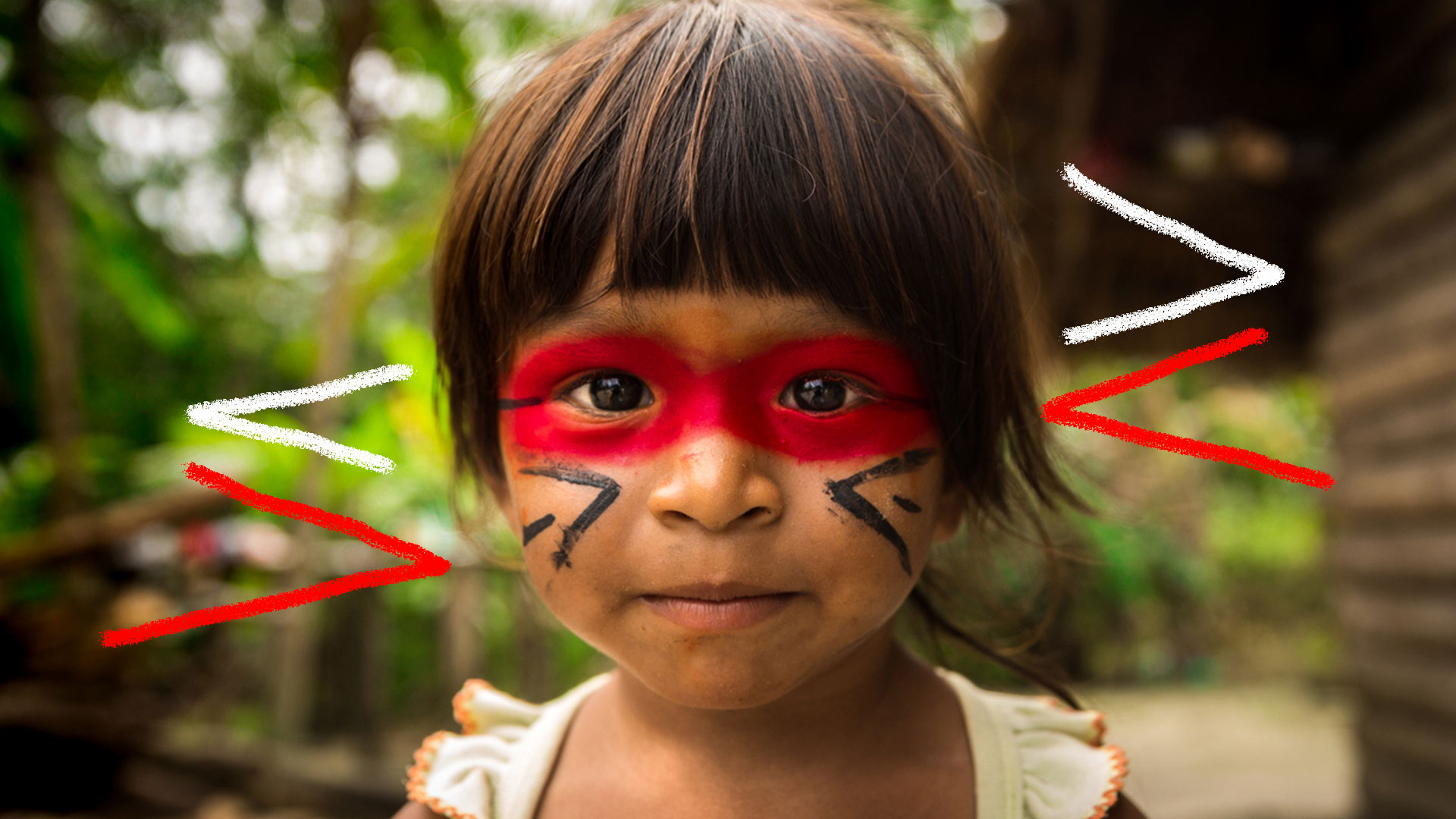 Criança indígena com o rosto pintado de urucum olhando para a foto