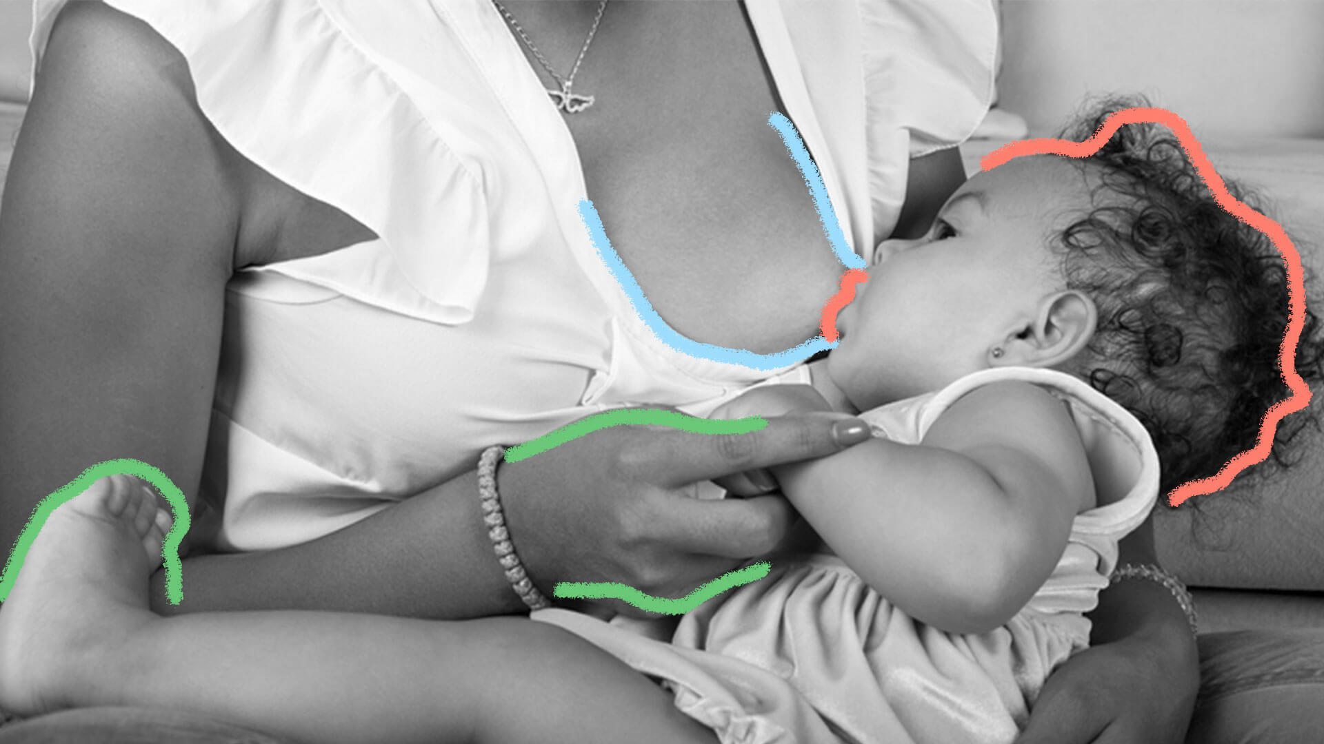 Foto em preto e branco mostra bebê sendo amamentado no colo da mãe.