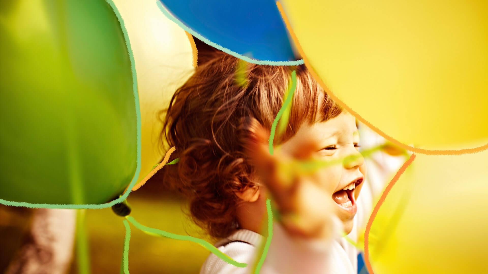 Criança sorrindo, com muitos balões em volta de si.