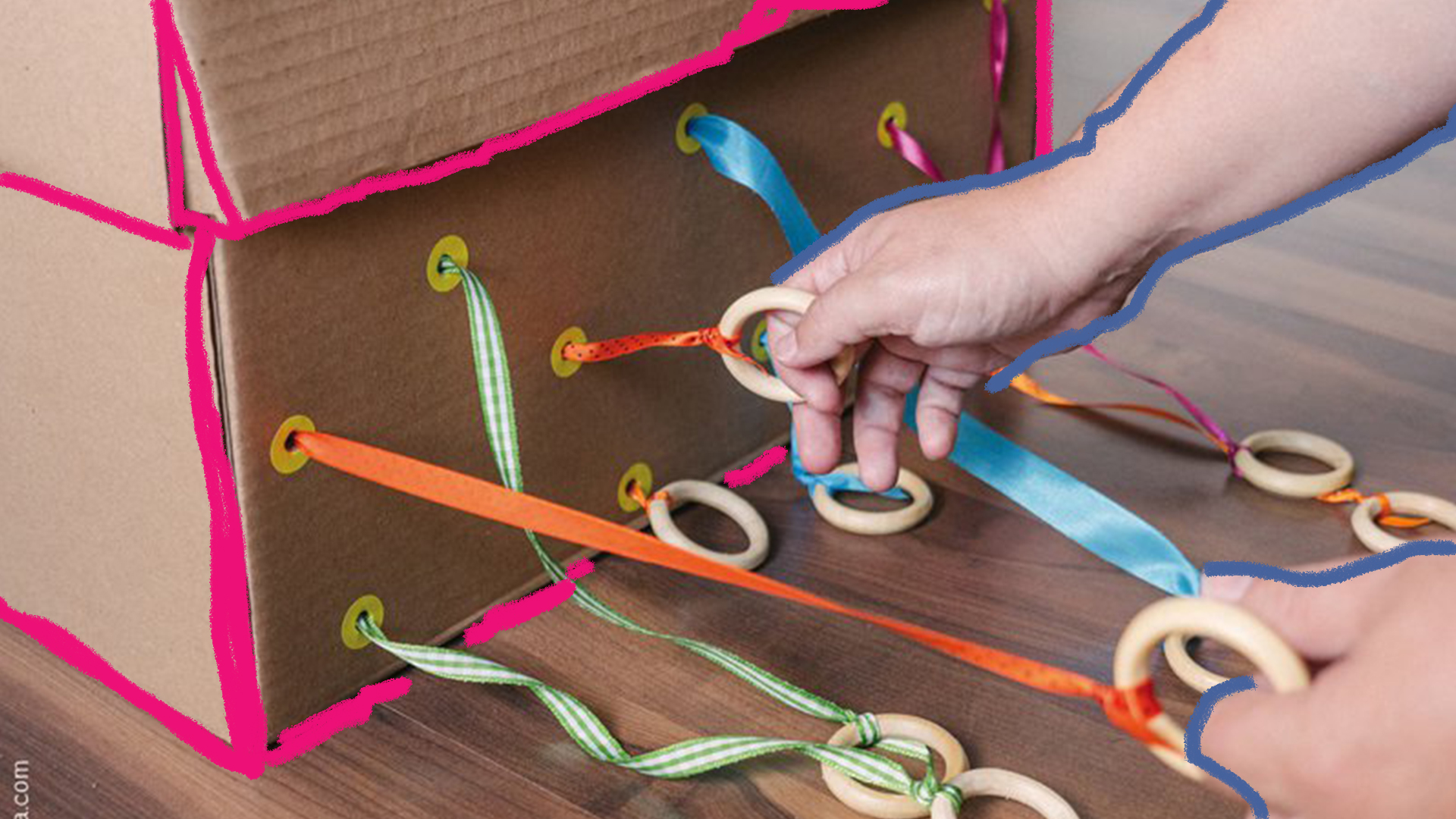 Caixas sensoriais: foto de mão de criança puxa fitas coloridas, que saem de uma caixa sensorial.