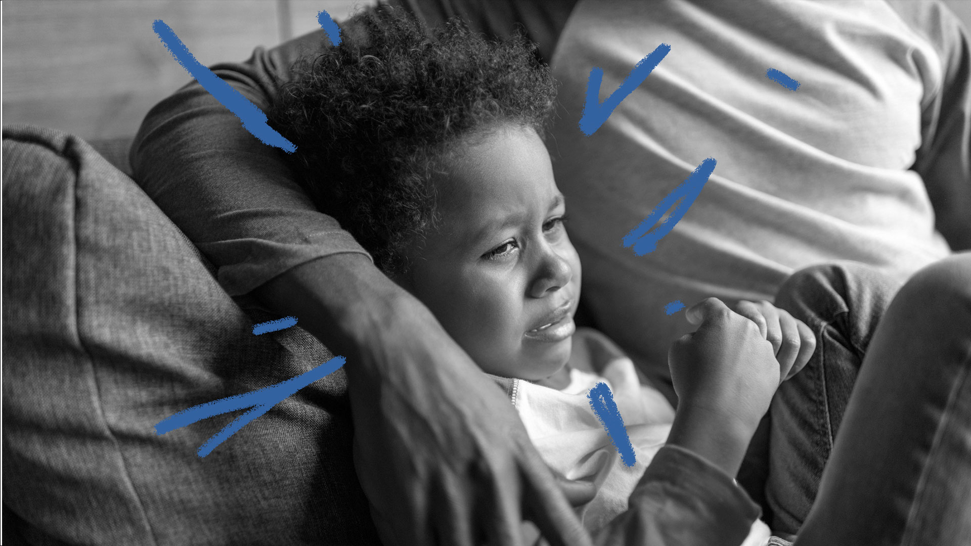 Racismo na escola: foto em preto e branco de uma criança negra, chorando, abraçada por um adulto