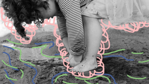 Menina brinca com os pés e as mãos na lama. Foto em preto em branco.