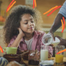 iogurte em casa: Mãe de homem negro servindo iogurte para menina negra que olha para o copo