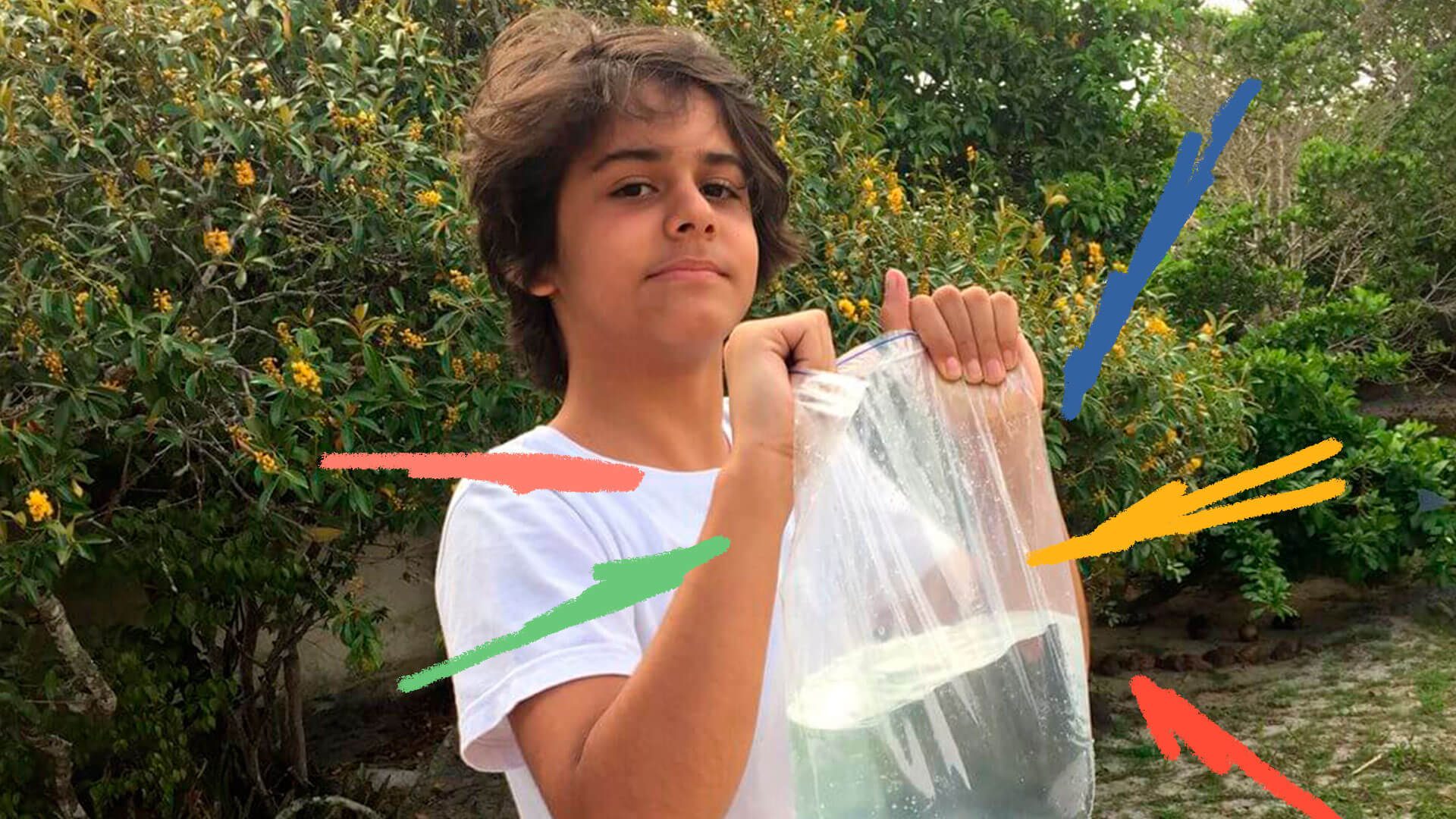 Um menino segurando um saco plástico transparente cheio de água dentro
