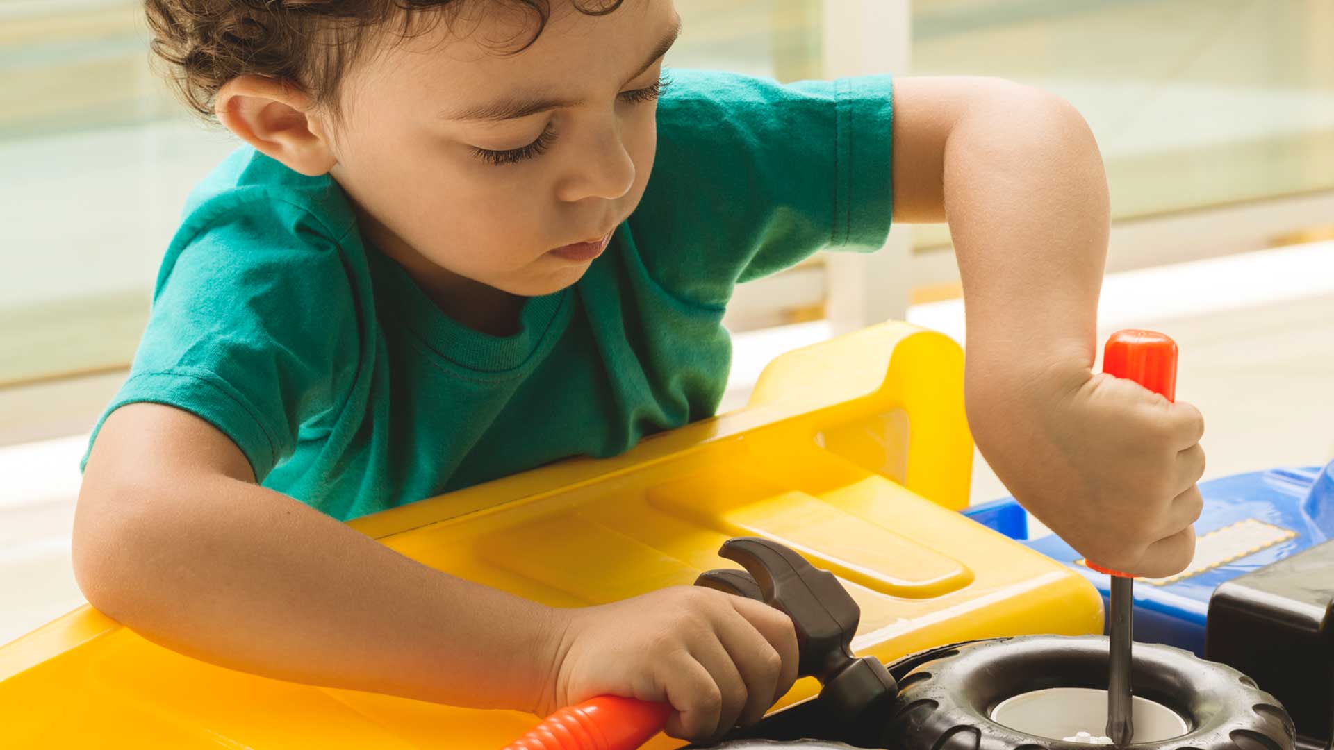 menino brincando com um caminhão de brinquedo