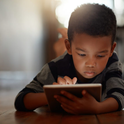 As mãos de uma criança, desenhando um boneco azul na tela de um tablet. Imagem usada para ilustrar a questão com o jogo blox, e a limitação do chat e verifericação de idade