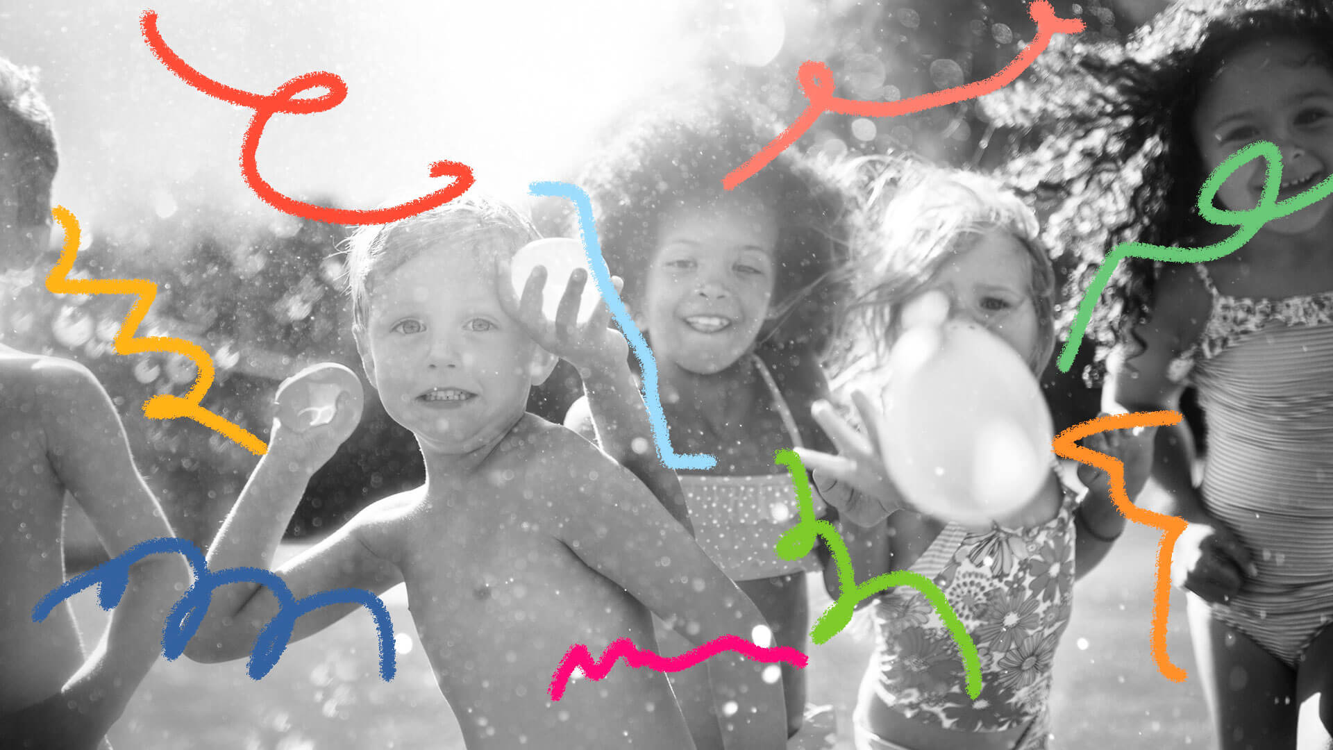 Três crianças (um menino e duas meninas) brincam com bexigas d'água.