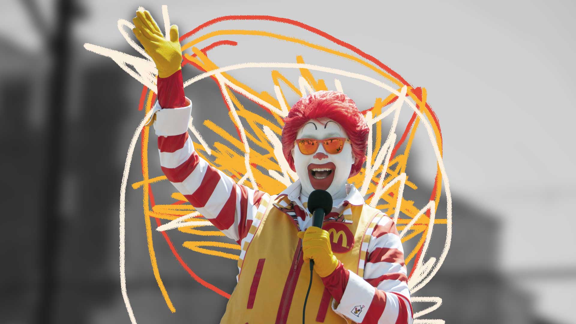 Fundo em preto e branco, no centro da foto vemos o palhaço Ronald McDonald, cercado por intervenções de giz em vermelho e amarelo.