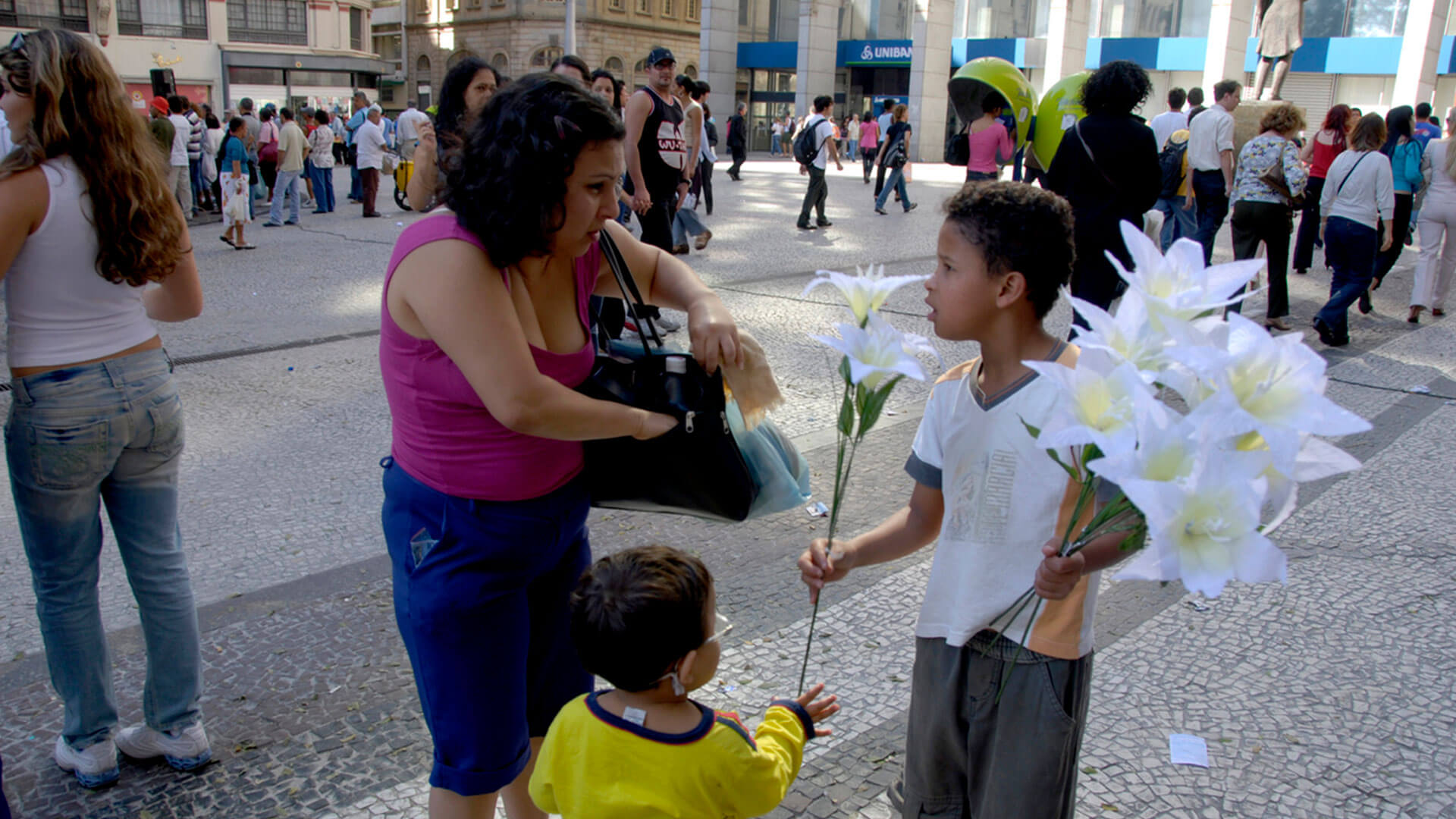 No centro do Rio de Janeiro. um menino vende flores para uma mulher na rua