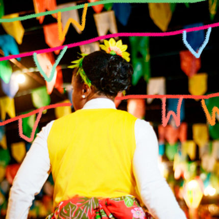 Criança de costas em uma festa junina, cheia de bandeirolas coloridas