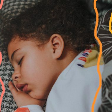 Sono tranquilo: foto de menino negro que dorme tranquilamente em cima de uma cama com lençol quadriculado.