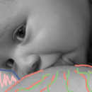 Imagem em preto e branco mostra rosto de um bebê enquanto mama.