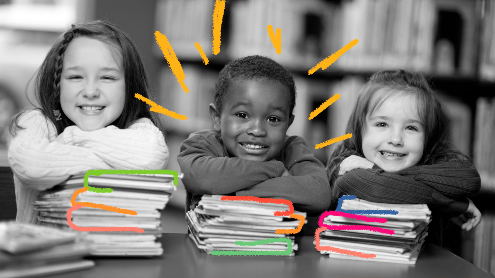Crianças se debruçam sobre uma mesa repleta de livros empilhados.