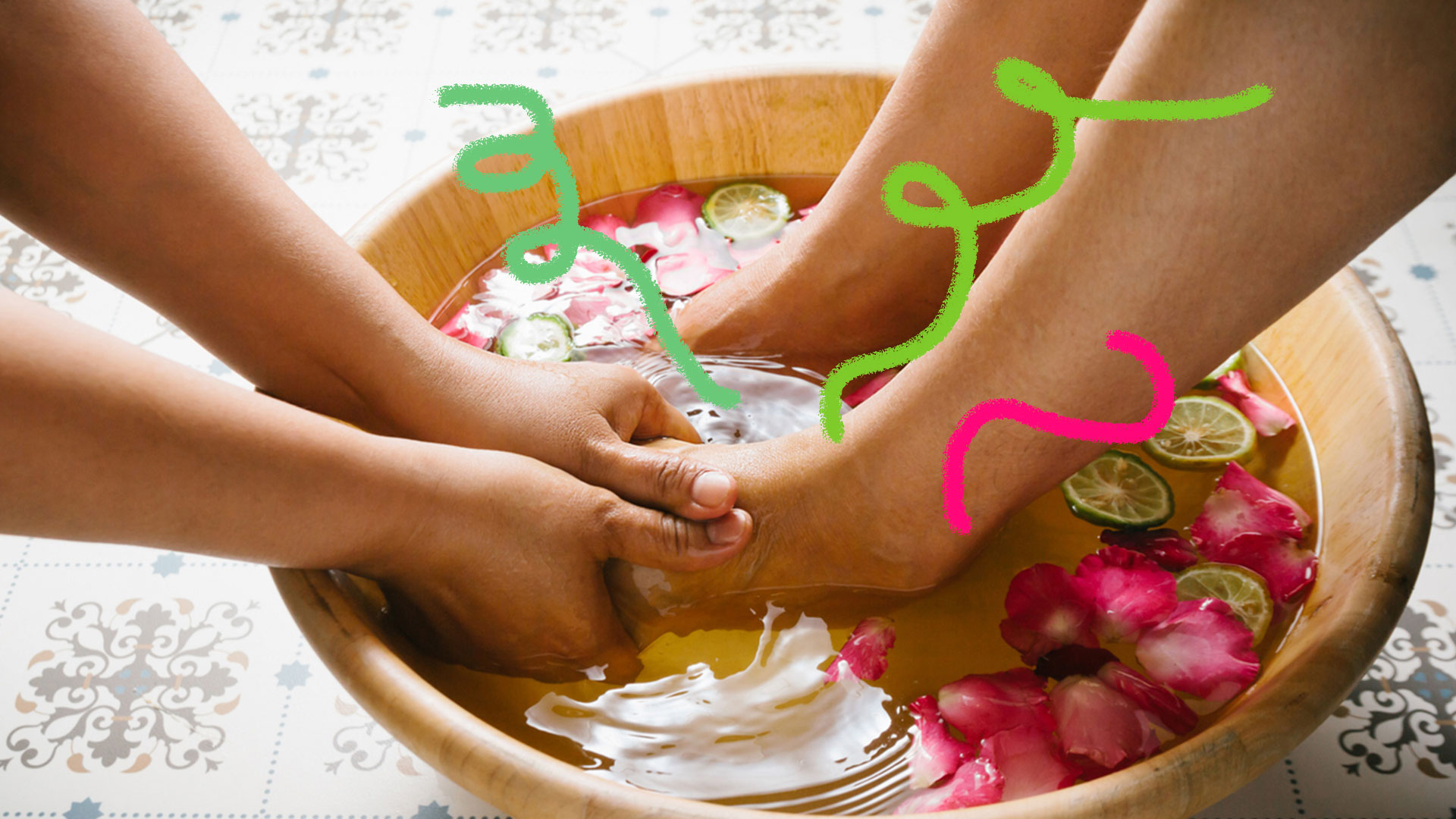Uma bacia com ervas, flores e água quente. Mãos fazendo massagem nos pés.
