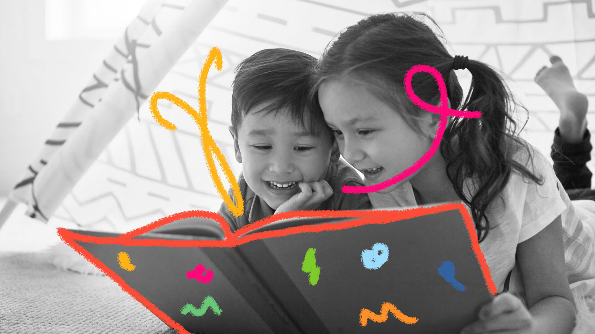 Um menino e uma menina estão brincando de cabaninha e lendo um livro. Os dois estão sorrindo e parecem deslumbrados.