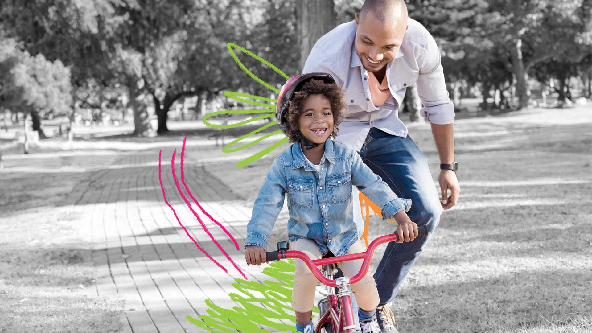 Frases positivas para crianças: foto de um garoto que sorri andando de bicicleta enquanto seu pai o incentiva logo atrás.