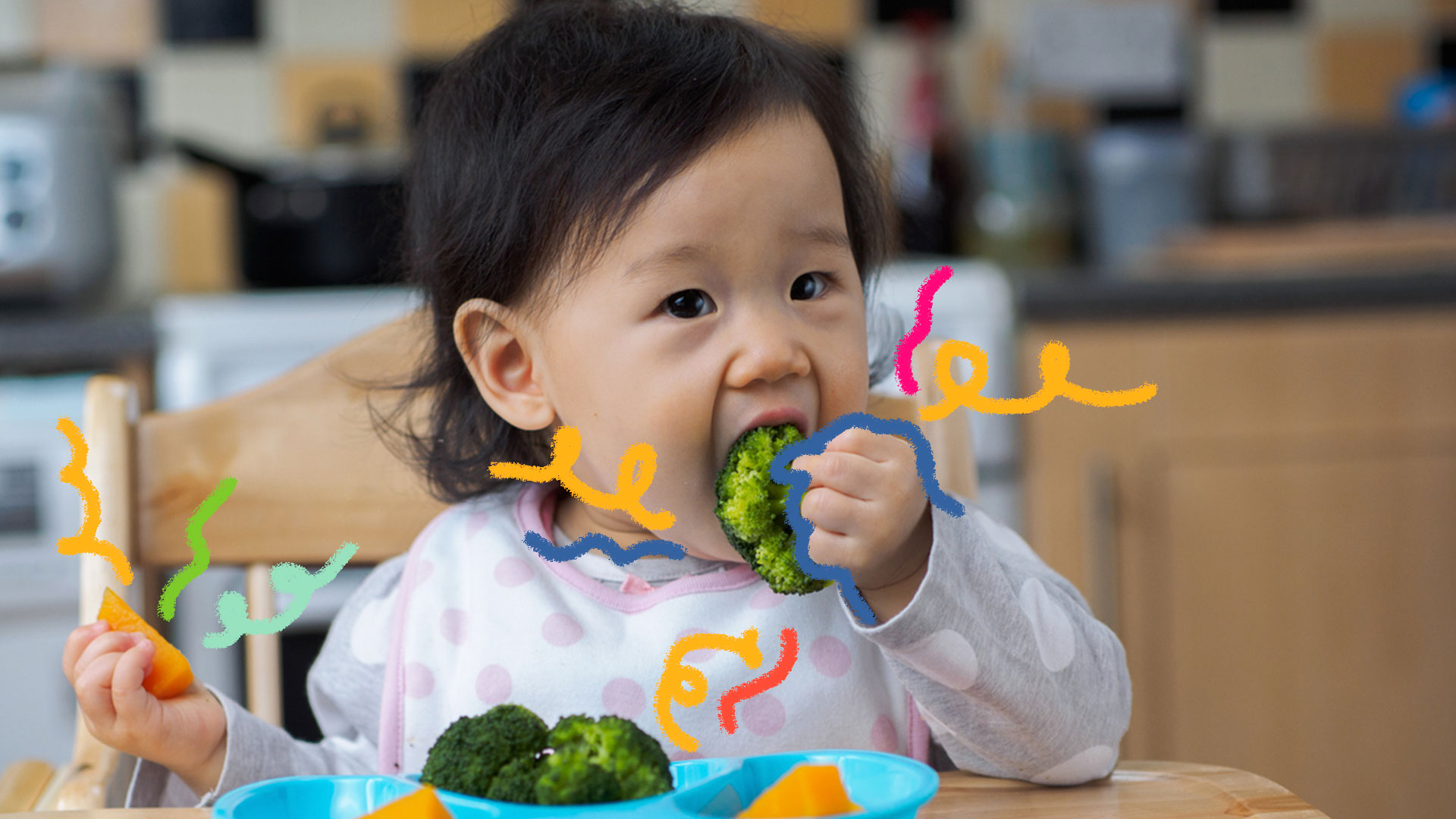 Menina oriental, de cabelos pretos, come o brocólis que está em seu prato azul claro em cima de uma mesa de jantar.