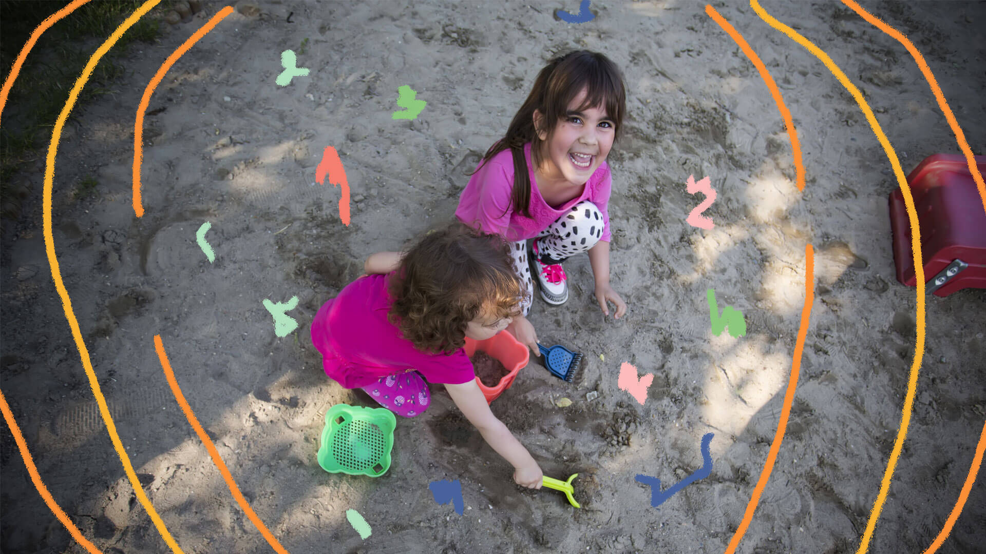 Duas meninas brincando na areia de um parque.