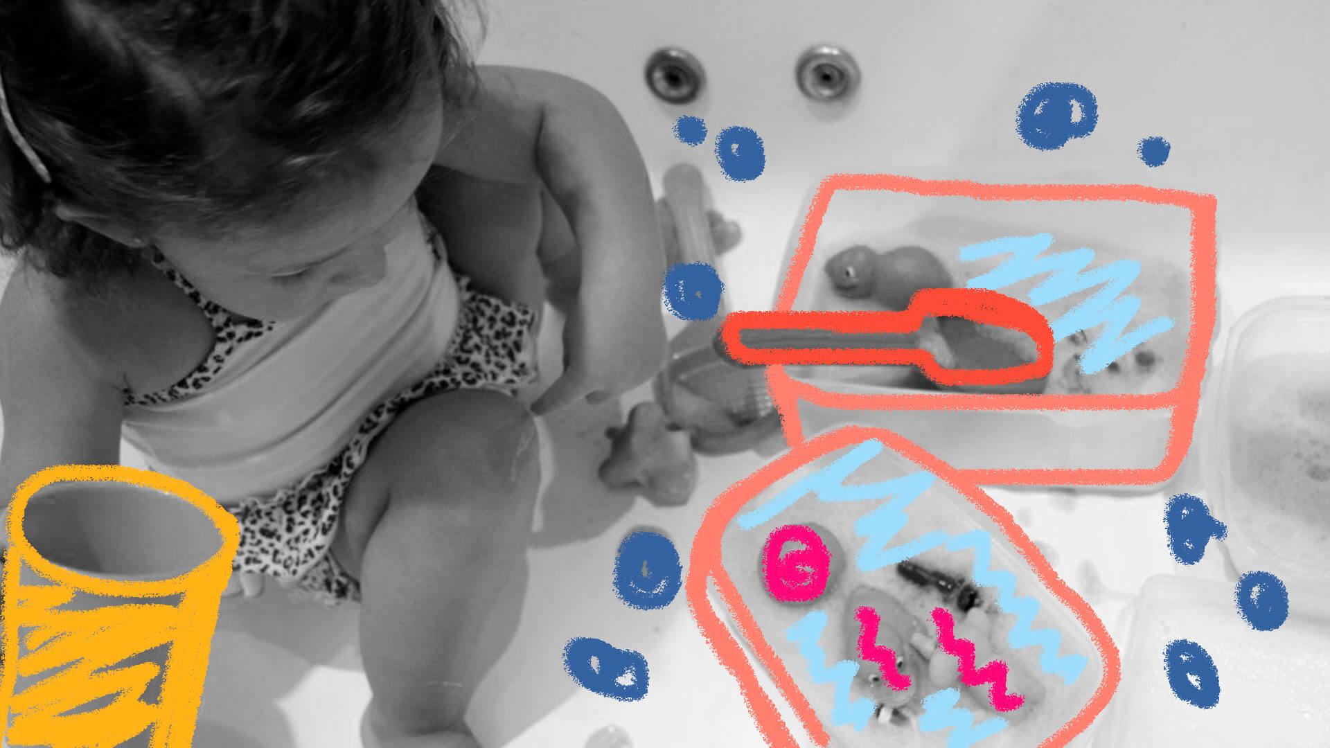 Uma criança está agachada no chão brincando com espuma, água e brinquedos de banho