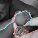 Mãos segurando as mãos de uma mulher deitada de bruços. Foto em preto e branco.