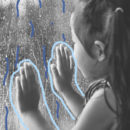Foto em preto e branco mostra uma menina tocando uma janela com as duas mãos, enquanto observa a chuva que cai lá fora.