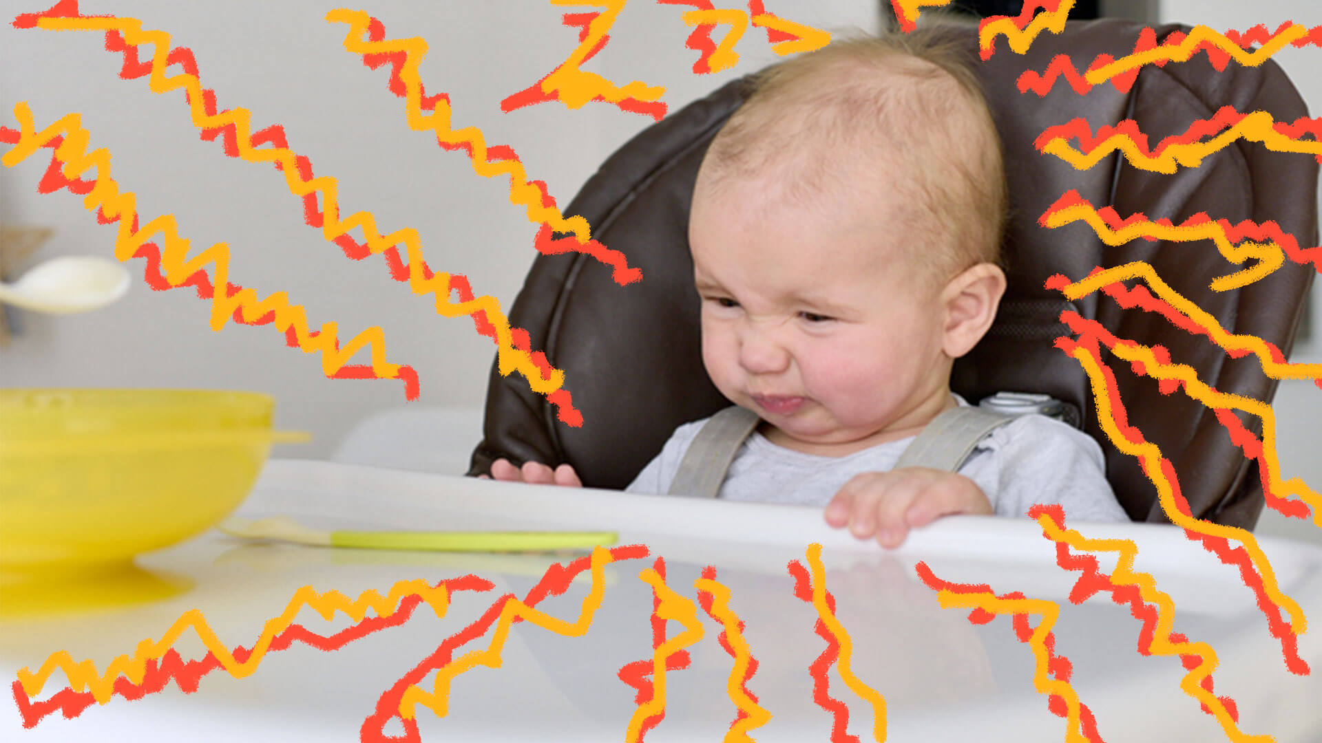 Bebê em um cadeirão faz careta para a comida que está na mesa.