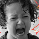 Foto em preto e branco mostra close de um menino chorando com a boca aberta.