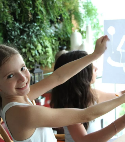 arte para crianças: foto de uma menina sorrindo com uma pintura feita em papel nas mãos