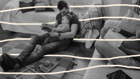 foto em branco mostra homem sentado no chão lendo para uma bebê no colo