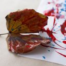 Folha de árvore marrom com tinta vermelha em um papel branco