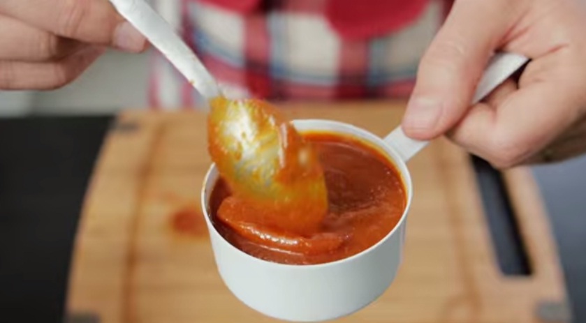 Receita de ketchup caseiro: foto de uma pote com ketchup e uma colher que mexe nele.