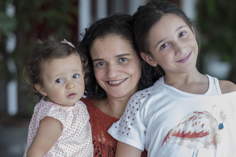 Patrícia Marinho: foto de uma mulher que sorri e tem duas crianças ao seu lado, que olham para a foto.