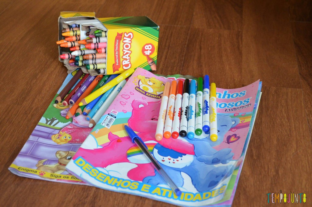 Foto de dois cadernos para colorir e uma caixa de giz de cera e canetinhas coloridas