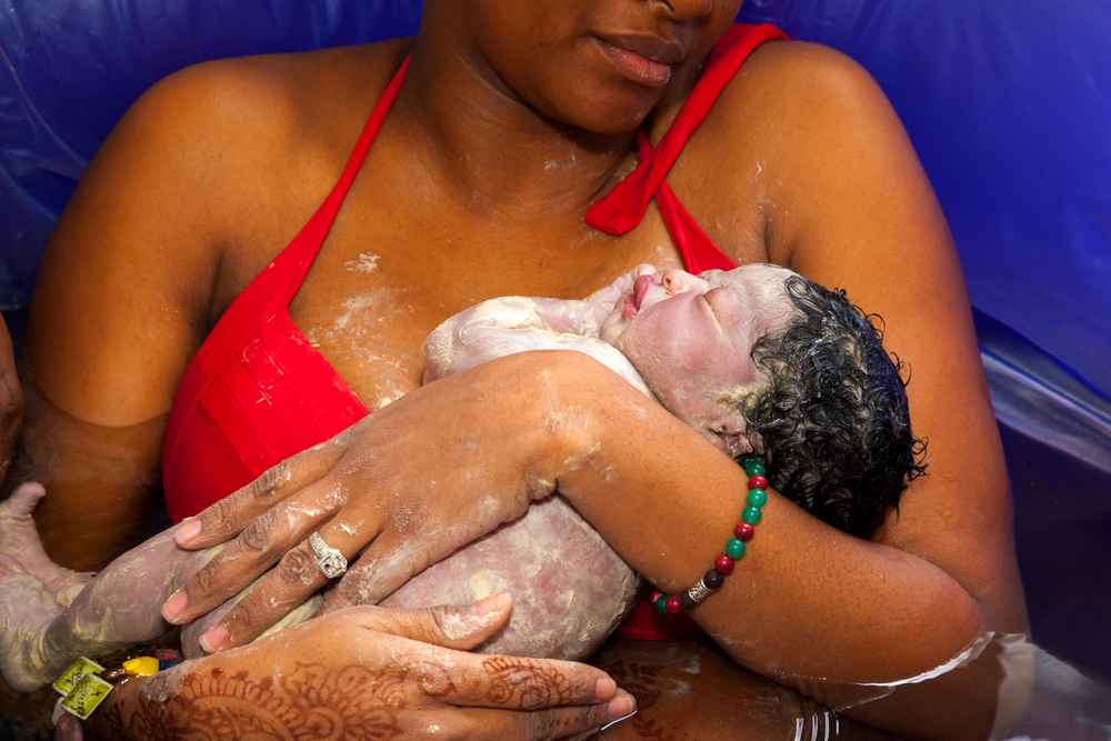 Uma mulher está segurando o bebê recém-nascido no colo.