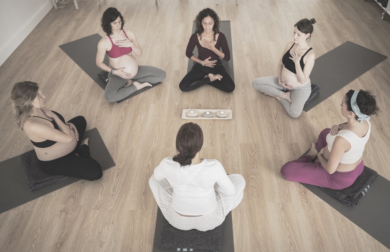 Mulheres sentadas em roda, praticando yoga.