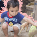 Crianças aprendem enquanto brincam: Um menino branco de cabelos pretos e camiseta azul, com bermuda branca, está brincando na areia