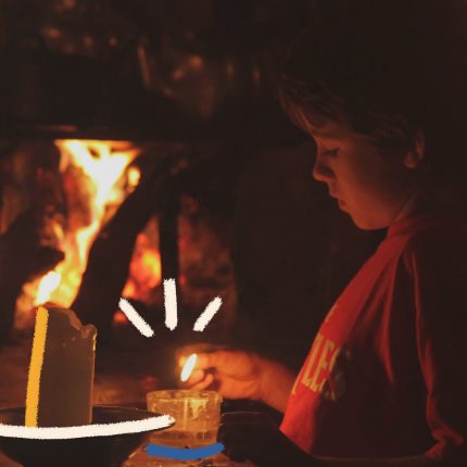 Um menino de perfil está sentado diante de uma fogueira