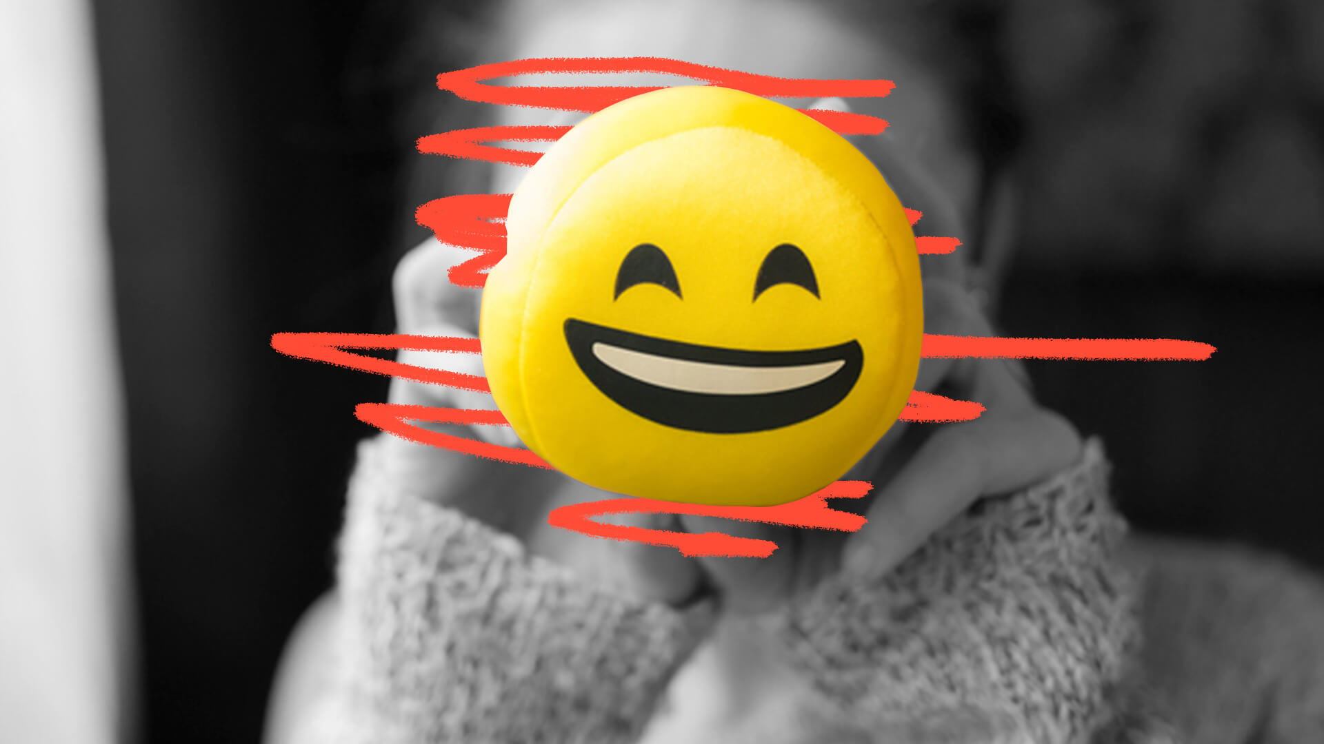 Menina segurando um emoji de pelúcia na frente do rosto