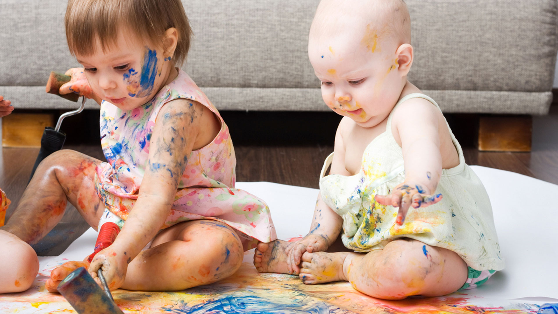 Dois bebês brincando com tintas coloridas