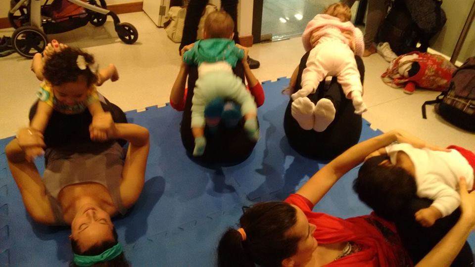 Bebês e famílias praticando yoga em tapetes no chão