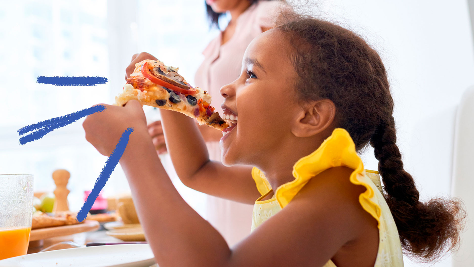 Menina comendo pedaço pizza com as mãos, sorrindo e olhando para frente.