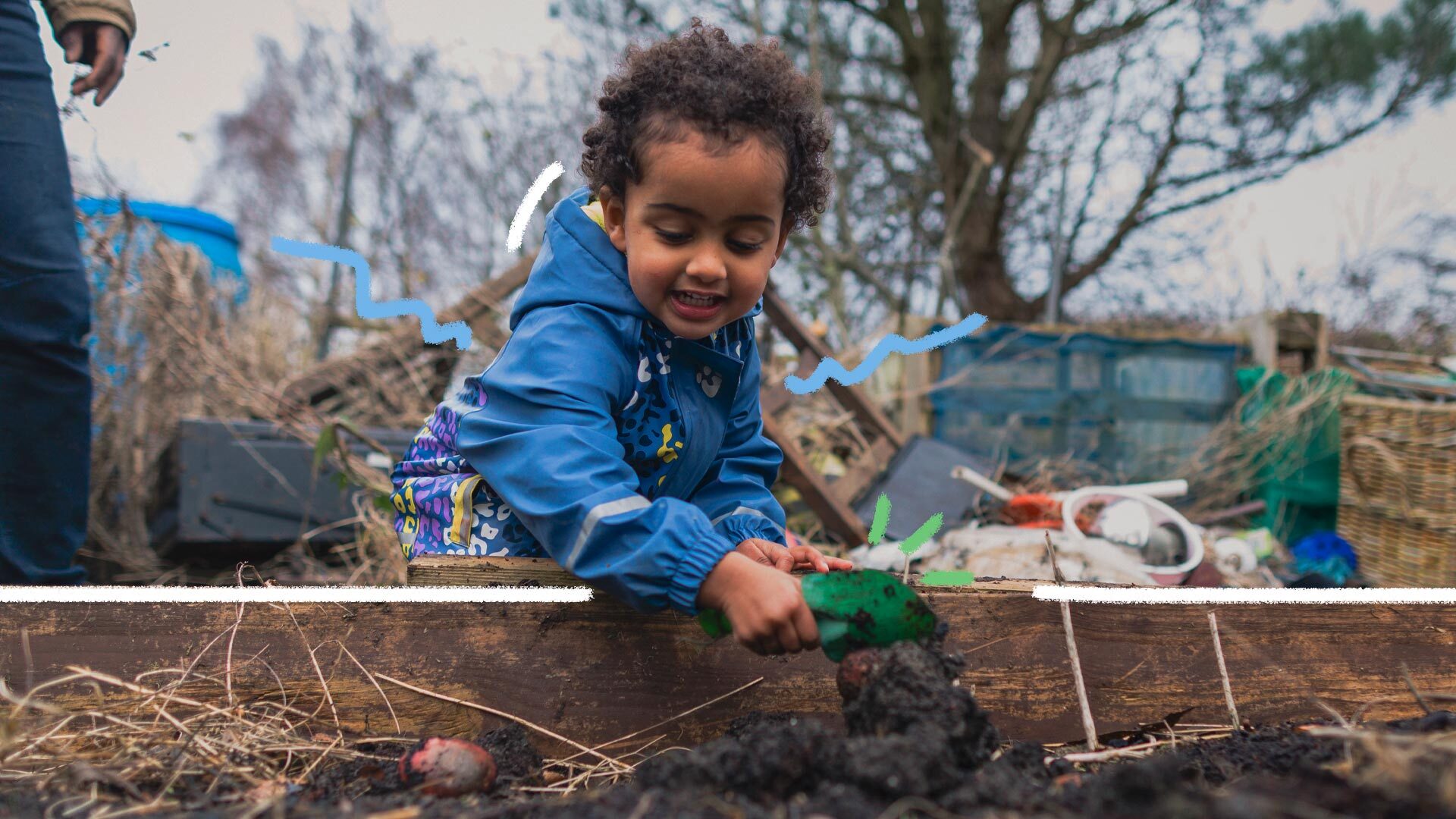 Agroflorestas: uma crianças de pele negra, usando jaqueta azul, está com uma muda de planta nas mãos e colocando na terra